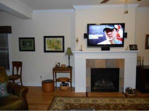 A living room setting with a white mantled fireplace and a TV on the top 